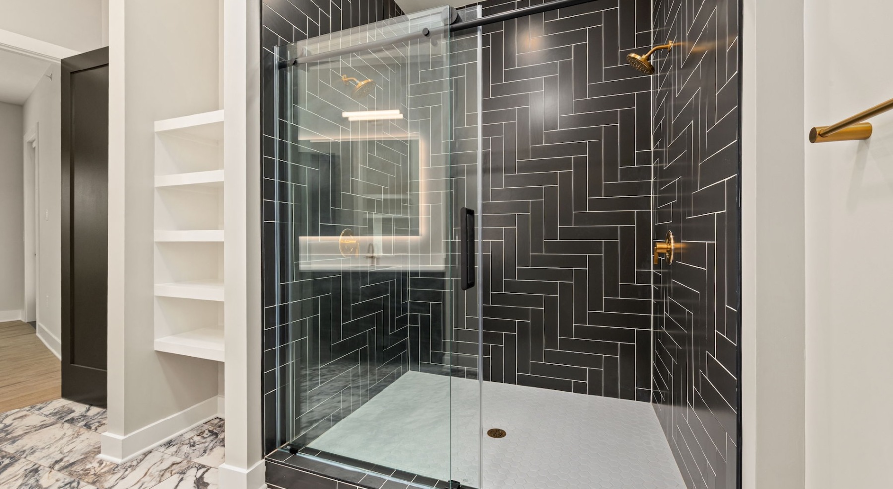 a spacious bathroom with a large mirror, glass shower,  and ample light